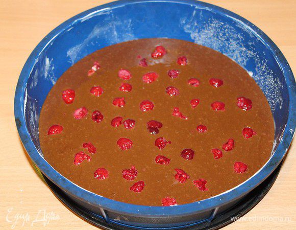 Выложить в форму 24 см половину теста. Затем выложить малину.