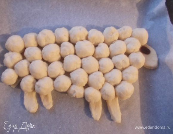 Каждый шарик укладываем вместо шерсти на барашка. Не забывайте,что тесто будет расти,поэтому скатывайте шарики и укладывайте так,чтобы они потом не разрослись по всему противню,делайте на треть их меньше,чем хотите получить в конечном итоге. Глаз я сделала из изюма,можно из орешка. Смазать взбитым яйцом и отправить в разогретую духовку 190С. ока не появится золотистая корочка.