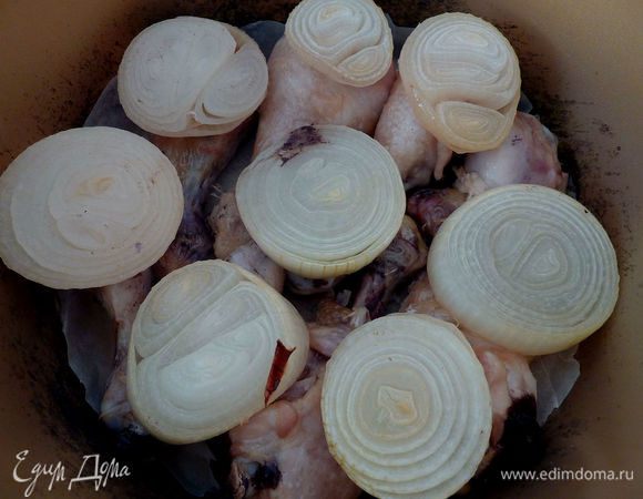 Раскладываем на дно куриные ножки. Сверху слой лука.

