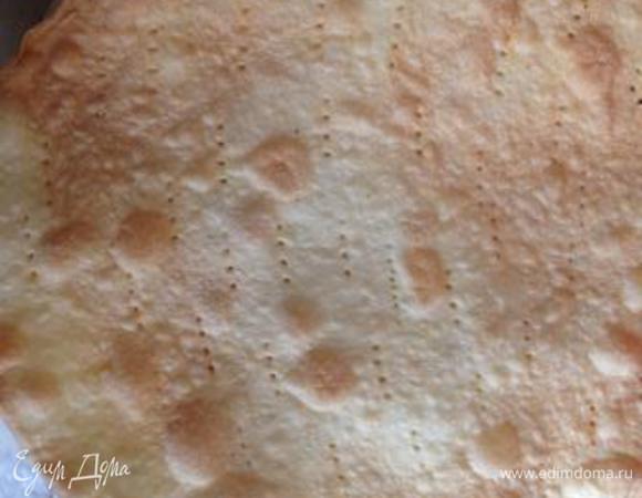 Наколоть корж вилкой и отправить вместе с пергаментом и обрезками в разогретую до 200 градусов духовку подрумяниться на несколько минут.