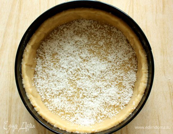 Перенести тесто в форму с помощью скалки и сформировать ровный бортик высотой 4 см. Дно часто наколоть вилкой, а затем присыпать оставшейся кокосовой стружкой.