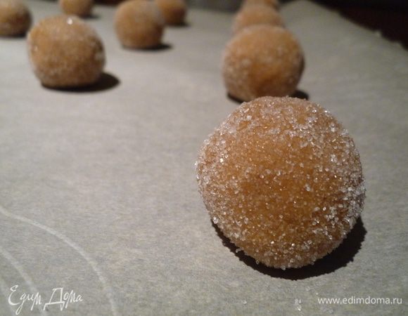 В небольшую миску высыпьте белый сахар.
Из остывшего теста, набирая по чайной ложке, сформировать шарики. Каждый вывалят в сахаре и разместить на противне на расстоянии 5 см.