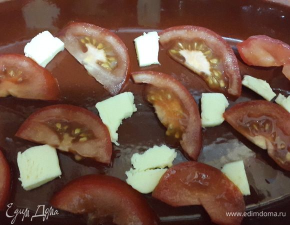 В глиняную тарелку равномерно выложить сливочное масло кусочками и помидоры.