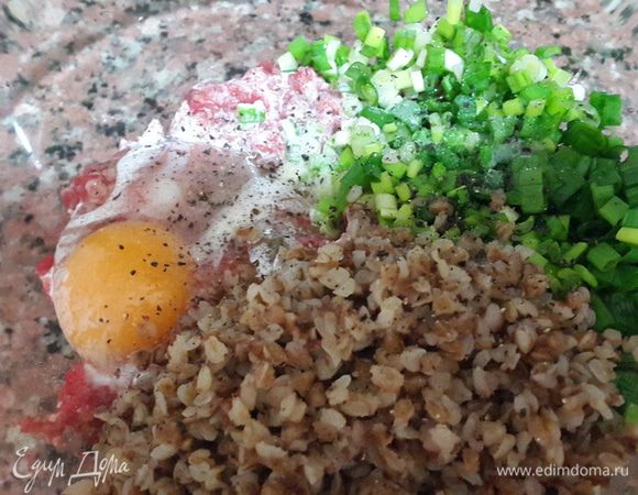 В фарш вбить яйцо, посолить, поперчить, добавить гречку, 2 ст. л. сливок и зеленый лук.