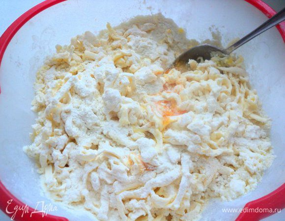 В миску высыпать 1 стакан муки, добавить творог и растереть руками в крошку.Яйца разделить на белки и желтки. Натереть на терке охлажденный маргарин в творожную крошку, добавить второй стакан муки, желтки, щепотку соли и соду, гашеную уксусом. 