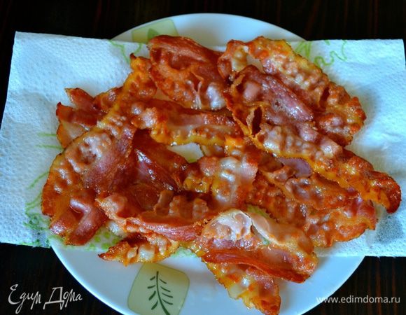 Нарезанный полосками бекон обжарить на сухой сковороде с двух сторон, чтобы он зажарился. Готовый бекон выложить на бумажное полотенце, чтобы убрать излишки жира.