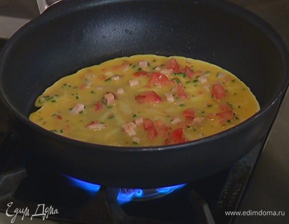 В тяжелой сковороде разогреть 1 ст. ложку оливкового масла и тонким слоем влить половину яичной смеси.