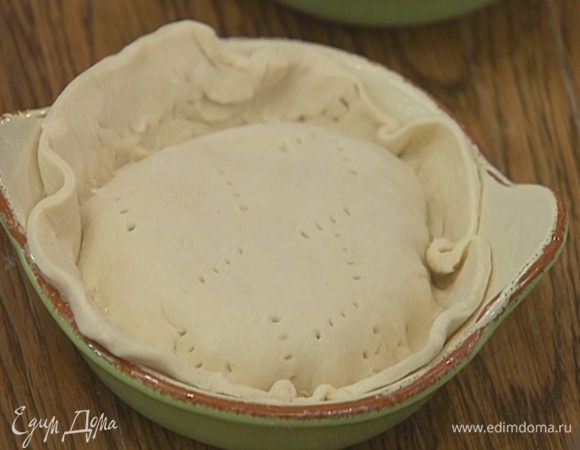 Две небольшие керамические формы смазать оставшимся сливочным маслом, выложить рыбу, вылить луковый соус и накрыть кружками из теста.