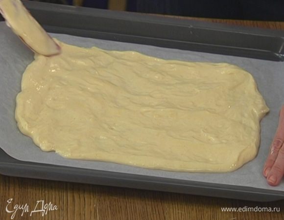 Противень выстелить бумагой для выпечки, смазать ее сливочным маслом, равномерно выложить тесто, так чтобы получился прямоугольник, и отправить в разогретую духовку на 6–7 минут.