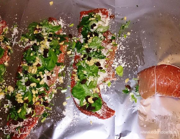 Рулеты посолить, поперчить. Тертый пармезан, рубленые петрушку, шнитт-лук и базилик, чеснок, орешки и изюм равномерно выложить на рулеты. Свернуть и закрепить либо кондитерской ниткой (у меня) либо зубочистками.