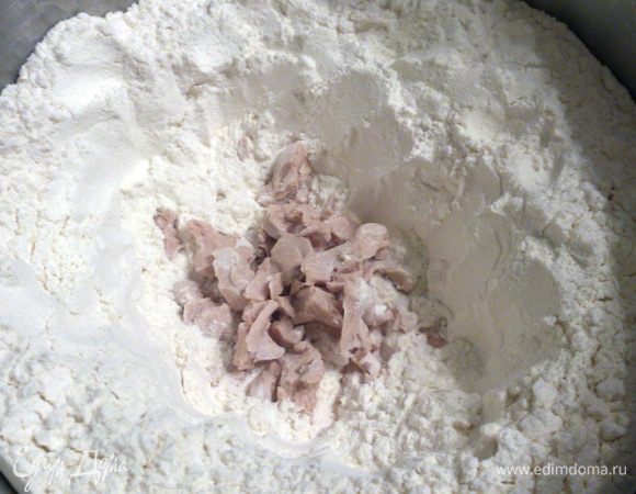 Просеять муку в миску, сделать в центре углубление и раскрошить туда дрожжи.