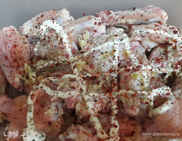 Крылышки моем, обрезаем кожу и кончики и разрезаем на 2 части. Выкладываем в емкость, солим, перчим, добавляем майонез, масло и чеснок.