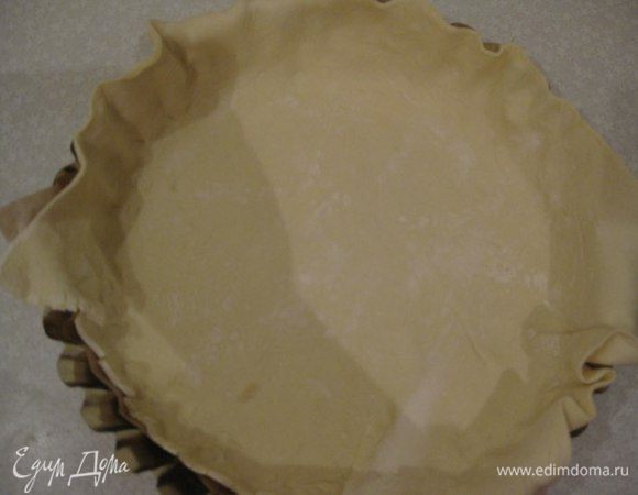 Слоеное тесто немного раскатываем, чтобы оно было толщиной 3 мм и выкладываем в форму. Обрезаем "свисающие" концы теста.