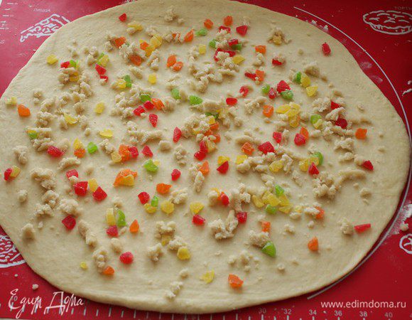 Раскатайте тесто в прямоугольник. Выложите цукаты и нарезанный небольшими кусочками марципан. 