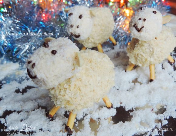 В туловищах проделываем 4 отверстия для ножек и одно сверху для крепления головы. Затем крепим на место голову, для пущей уверенности можно подклеить ее белым шоколадом, затем вставляем на место ножки. Все трещинки замазываем белым шоколадом и присыпаем вафельной крошкой.
Нам осталось нарисовать овечкам мордочки растопленным черным шоколадом. Им же я нарисовала копытца.