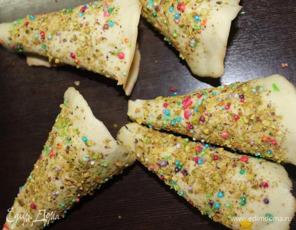 Снимаем круги ПО ОДНОМУ! С пергамента, поддевая края ножом, и руками сворачиваем их конусом посыпкой наружу, тщательно придавливая места стыков, чтобы они хорошо скрепились. Елочки, пока горячие, хорошо крепятся в местах, где посыпки меньше. Если вы когда-нибудь работали с такого рода изделиями, пекли, например, печенье "Каллы", то у вас проблем точно с этим делом не возникнет.

Оставляем остывать, положив елочки на шов.
Поступаем так же с оставшимся тестом, меняя каждый раз бумагу. Кстати, бумагу важно использовать качественную, либо лучше воспользоваться фольгой. Последнюю партию я делала на ней и мне так даже больше понравилось, тесто лучше отходило. 
Если делаете одну партию, то можно просто выложить тесто на промасленный противень.