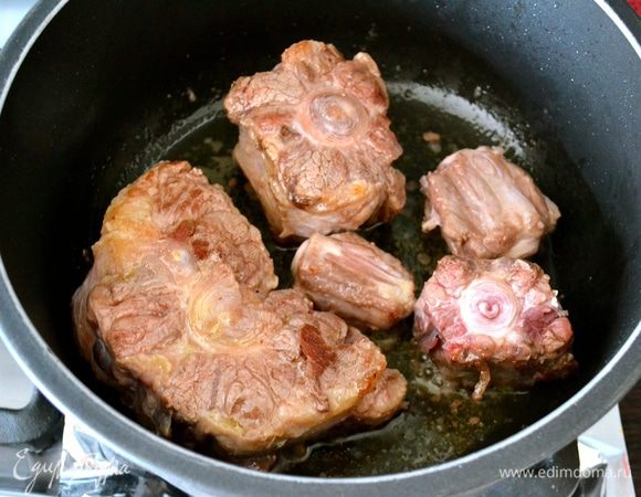 В кастрюле с толстым дном нагреть масло и обжарить куски мяса со всех сторон на сильном огне до лёгкой корочки. Достать и выложить мясо в глубокое блюдо, поддерживать в теплом состоянии.
