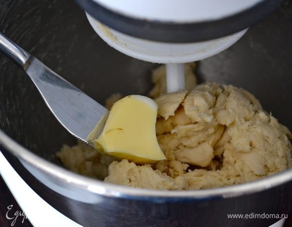 В процессе замешивания начать добавлять кусочками размягченное сливочное масло и кулинарный жир. Каждый кусочек добавляем только после того, как предыдущий полностью перемешался с тестом. 