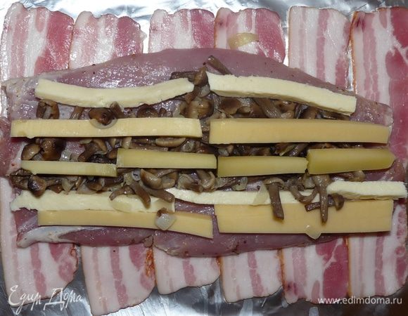 Выложить на фольгу полоски бекона. На бекон положить пласт вырезки.
На пласт выложить рядами начинку.