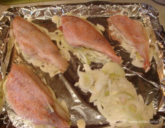 На противень кладем фольгу, смазываем подсолнечным маслом. Порезать крупно лук, сверху выложить рыбу (рыбку лучше скрепить деревянными шпажками, при готовке края могут подняться).