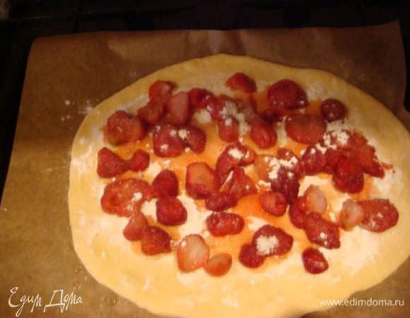 Меньшую часть теста раскатать, посыпать крахмалом, сверху выложить ягоды, сахар по вкусу, края загнуть.