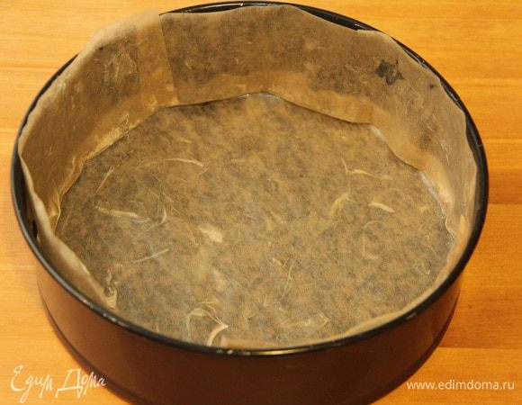 Прежде всего подготовить форму для выпечки коржа-основы: понадобится разъёмная форма диаметром 20 см (высотой 10 см), вырезать из пекарской бумаги круг подходящего диаметра, полоску для боковины. Смазать их сливочным маслом.