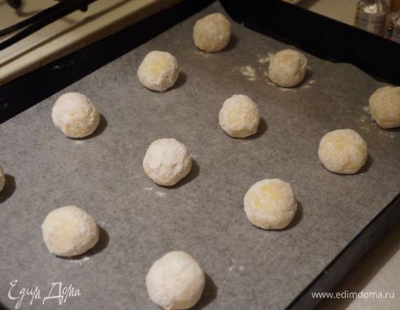 Скатываем шарики, обкатываем в сахарной пудре, выкладываем на пергамент и печем минут 11-14. Остужаем на решетке