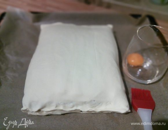 Заверните рулет в тесто, защипните краешки теста. Смажьте желтком. 