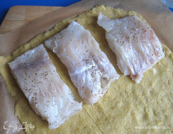 Филе трески посолить, поперчить, сбрызнуть лимонным соком. Духовку разогреть до 170 градусов. Бумагу для запекания с миндальным тестом вынуть  из холодильника и положить на него кусочки трески. Разрезать тесто на три равных части, после разделить каждую часть пополам и накрыть сверху рыбу кусочками теста. Чтобы отделить тесто от бумаги, понадобилась металлическая лопатка.