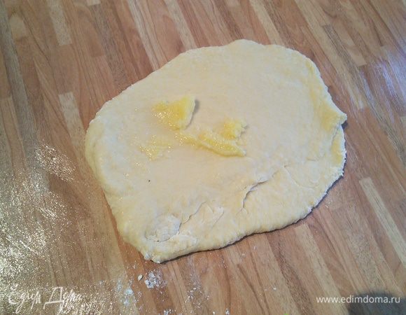 После этого смажьте рабочую поверхность размягченным топлёным маслом (можно заменить на сливочное или растительное). Тесто разделите на две части. Немного раскатайте и пальцами смажьте 10 г масла каждую из двух половин. 