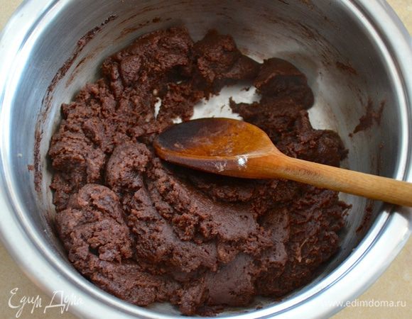 Как только вода с маслом закипит, всыпать разом муку с какао. Уменьшить огонь и продолжать варить, размешивая деревянной ложкой. Масса должна стать однородной и компактной, и начать отходить от стенок кастрюли. Снять с огня и остудить полученное тесто. Переложить в миску.
