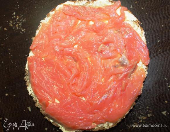 Получившиеся коржи смазываем сливочным маслом. 
На нижний корж выкладываем половину порезанного ломтиками лосося.