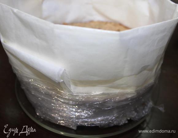 Теперь сооружаем конструкцию вокруг основы нашего торта, в которую будем заливать слой мусса. Для этого оборачиваем коржи несколькими слоями пергамента (фольги), сложенного полосами нужной высоты, и для надежности обматываем пищевой пленкой, чтобы конструкция хорошо держалась. Мне для этого понадобилась вторая пара рук.