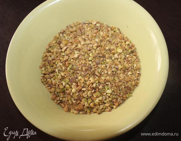 Заранее подготовим орехи.
Если у вас есть очищенные несоленые, то просто измельчаете их (не совсем в муку, а чтобы они чувствовались в выпечке). 
Если же, как в моем случае, фисташки соленые и неочищенные, то  чистим орешки от скорлупы и промываем в холодной воде. Подсушиваем на бумажном полотенце, а затем на горячей сковороде без масла. А затем измельчаем.
Для получения 100 граммов мне понадобилось где-то 210-220 грамм неочищенных орехов. 
Для бисквита отмеряем 90 грамм, а остальные пойдут на украшение готового торта.