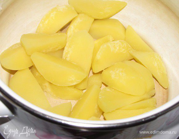 Небольшие картофелины очистить и порезать дольками. Залить кипятком и варить на сильном огне 7-10 минут. Слить картофельный отвар и вернуть кастрюлю с картофелем на огонь для того, чтобы выпарилась лишняя влага. Снять с огня и сохранять картофель теплым.