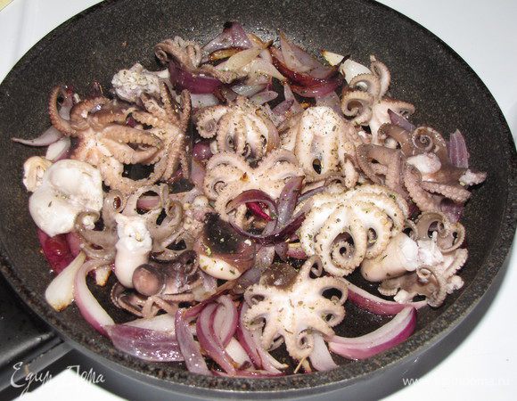 Добавить осьминогов, приправить орегано и обжарить на сильном огне.