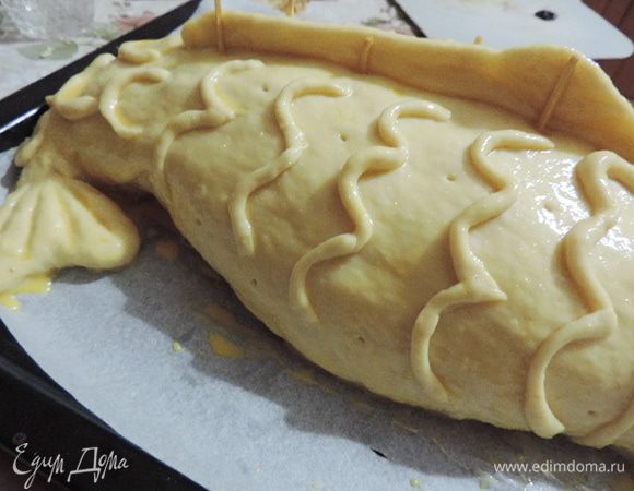 Оставшееся тесто раскатываем овалом большего размера, наматываем на скалку и переносим на "рыбку", скрепляем верхний и нижний края теста, подворачиваем шов под низ. Руками придаем кулебяке очертание рыбки. Постарайтесь ее сплюснуть к хвосту и немного загнуть хвостик на бок.
Не забываем про детали, именно они играют главную роль. Из оставленного теста делаем плавник, его устанавливаем на середину спинки, чтоб он не упал устанавливаем спички, предварительно убрав с них серу.