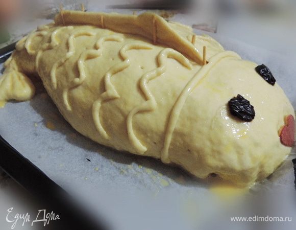 Ротик вырезаем из кусочка красного перца (у меня его не оказалось, пришлось использовать шкурку от граната), глазки - кусочки чернослива.
Не забываем сделать чешуйки. Для этого катаем из теста тонкие жгутики и приклеиваем к спинке, имитируя рисунок чешуи. Смазываем кулебяку желтками, смешанными с чайной ложкой молока, и делаем маленькие дырочки, чтоб выходил пар.