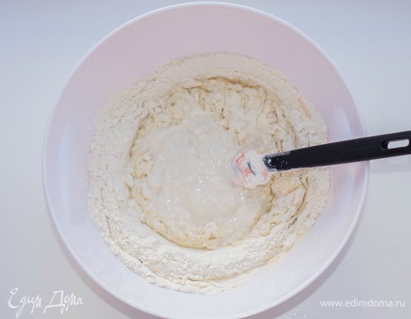 Приготовить тесто: в глубокую емкость налить кефир, посолить (примерно 0,5 ч.л.), постепенно (порционно) добавить муку, перемешивая лопаточкой после каждой порции. Перед последней порцией добавить соду, потом оставшуюся муку и хорошо перемешать.