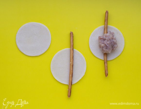 На каждый кружок из теста положить соленую соломку так, чтобы она на пару сантиметров выходила за края теста. В середину выложить фарш (примерно 1 ч.л. с верхом).