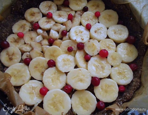 На слой стружки равномерно распределить оставшуюся крошку из орехов и семечек, аккуратно утрамбовать ее. Сверху опять выложить слой из бананов и клюквы. 