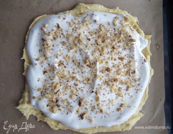 Поверх теста размазываем взбитые белки и посыпаем грецкими орехами. 