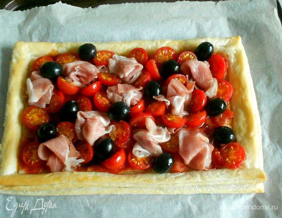 Достаньте из духовки заготовку и разложите ветчину и оливки. Запекайте ещё 5 минут.