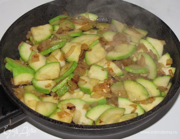 Разогреть в сковороде оливковое масло и обжарить мелко рубленный лук до прозрачности. Затем добавить цукини, нарезанные четвертинками. Жарить на сильном огне, часто помешивая, до полуготовности, в конце посолить и поперчить по вкусу. У меня небольшая сковорода, поэтому я жарила в два захода.  Вместо цукини я взяла  кабачки:) Готовую начинку выложить на тарелку и остудить.