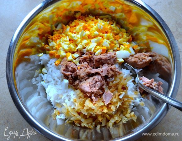 В миску выложить готовый рис, обжаренный лук, добавить порубленные яйца и тунца из банки.