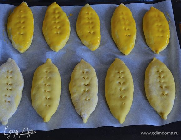 Через 15 минут смешать желток со сливками. По поверхности пирожков сделать ножницами косые надрезы (по желанию!) И смазать поверхность молочно-яичной смесью.  