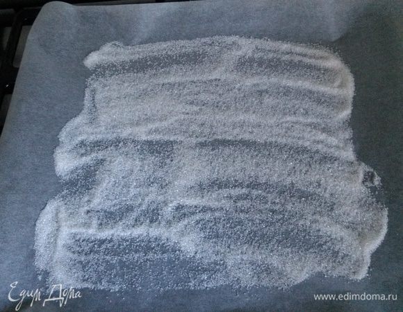 Апельсин нарезать тонко, высыпать на пекарскую бумагу на противень половину сахара.