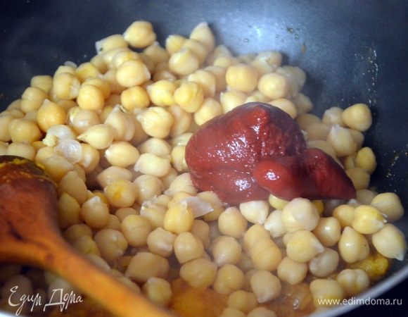 После этого в сковороду добавляем отваренный нут, томатную пасту, добавляем бульон (или воду), перемешиваем.