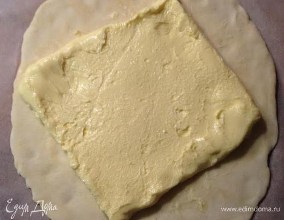 Рабочую поверхность присыпать мукой. Тесто раскатать в квадрат, толщиной прим. в 2 см. В центр положить квадрат из масла.