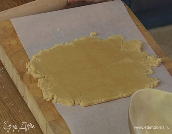 Рабочую поверхность выстелить бумагой для выпечки, выложить тесто, накрыть еще одним слоем бумаги и раскатать в пласт.